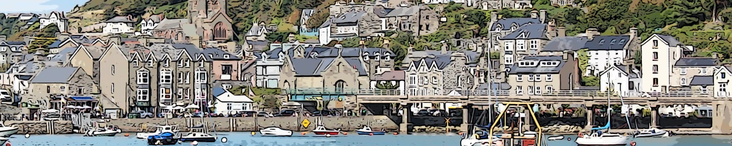 a view across the harbour of barmouth in wales with many small craft on the water